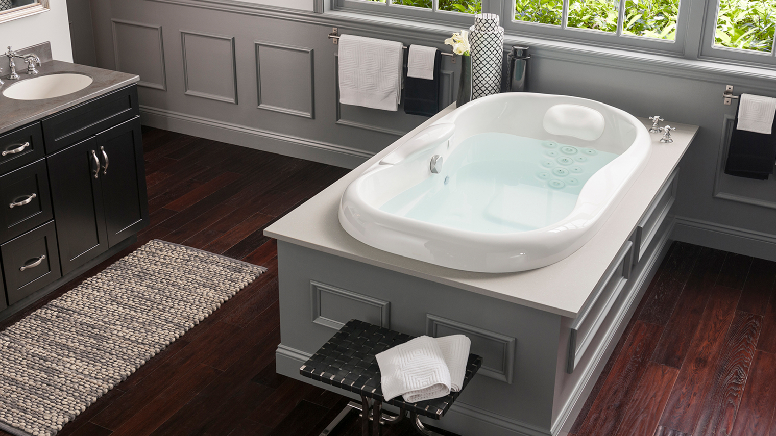 Whirlpool tub with center platform with wood flooring in the middle of the bathroom.