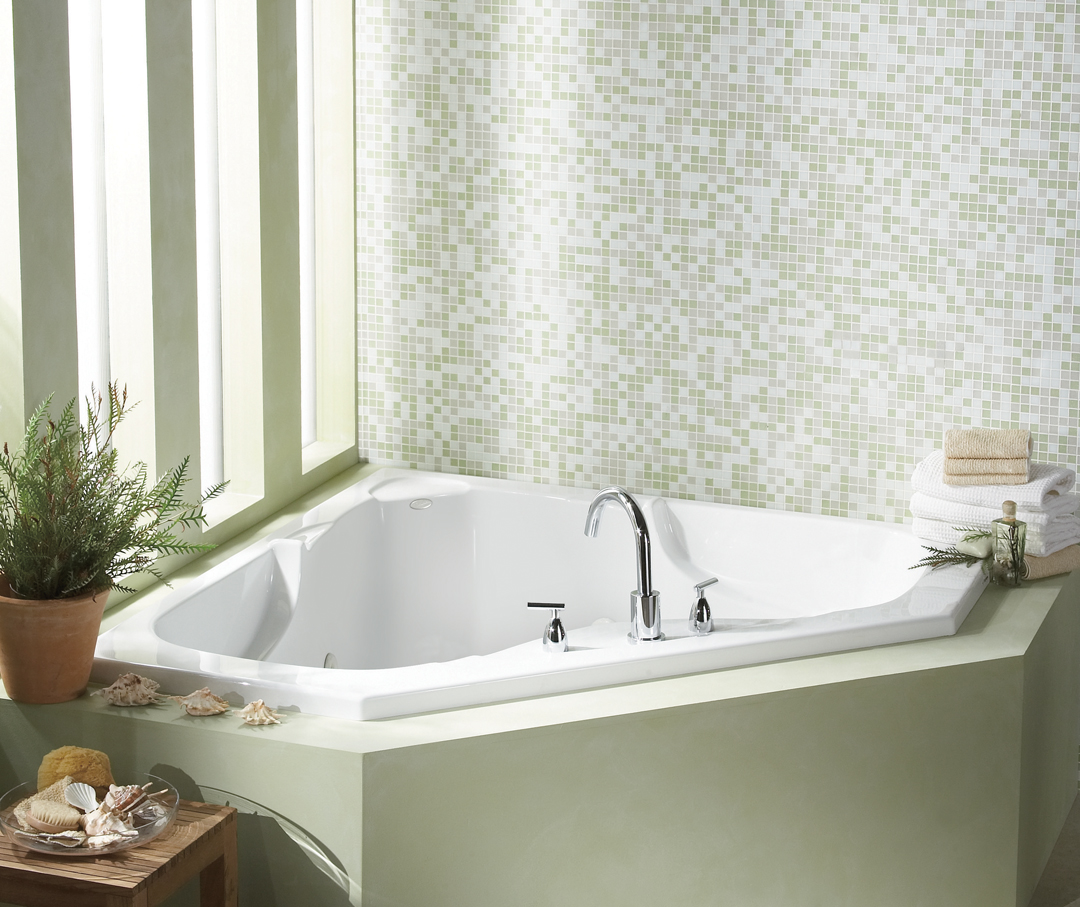 Tiled wall bath tub with a green interior next to some windows.