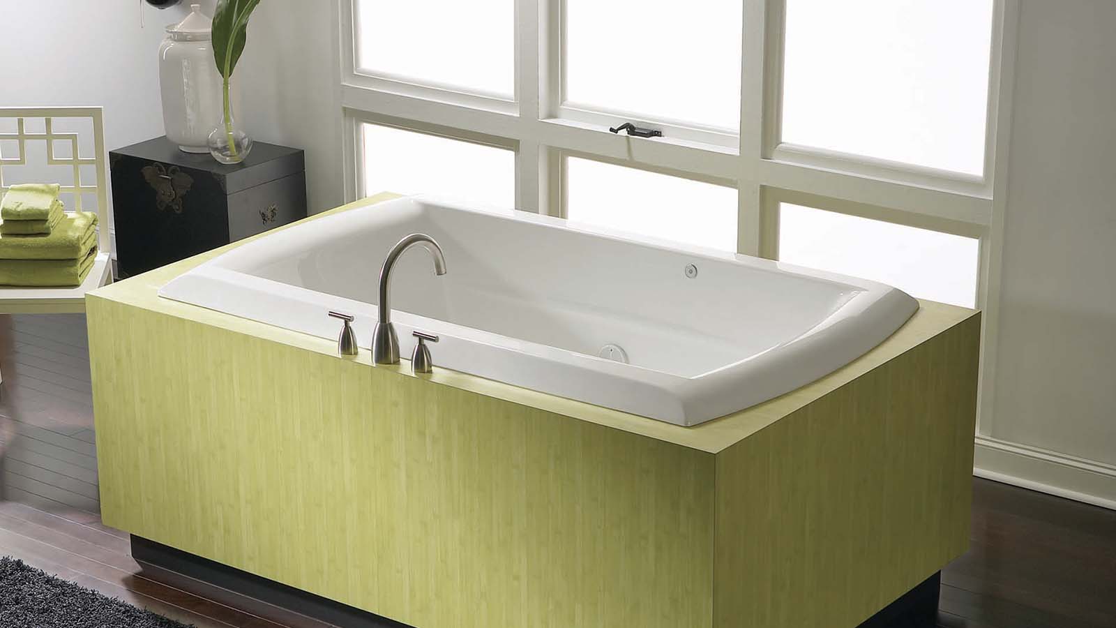 Image of a drop-in tub with a green frame skirt around it.