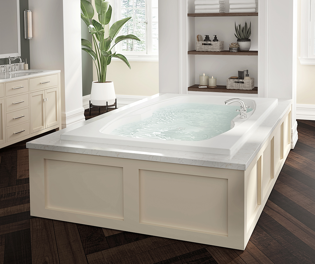 Large soaking tub in the middle of the bathroom with wood flooring.