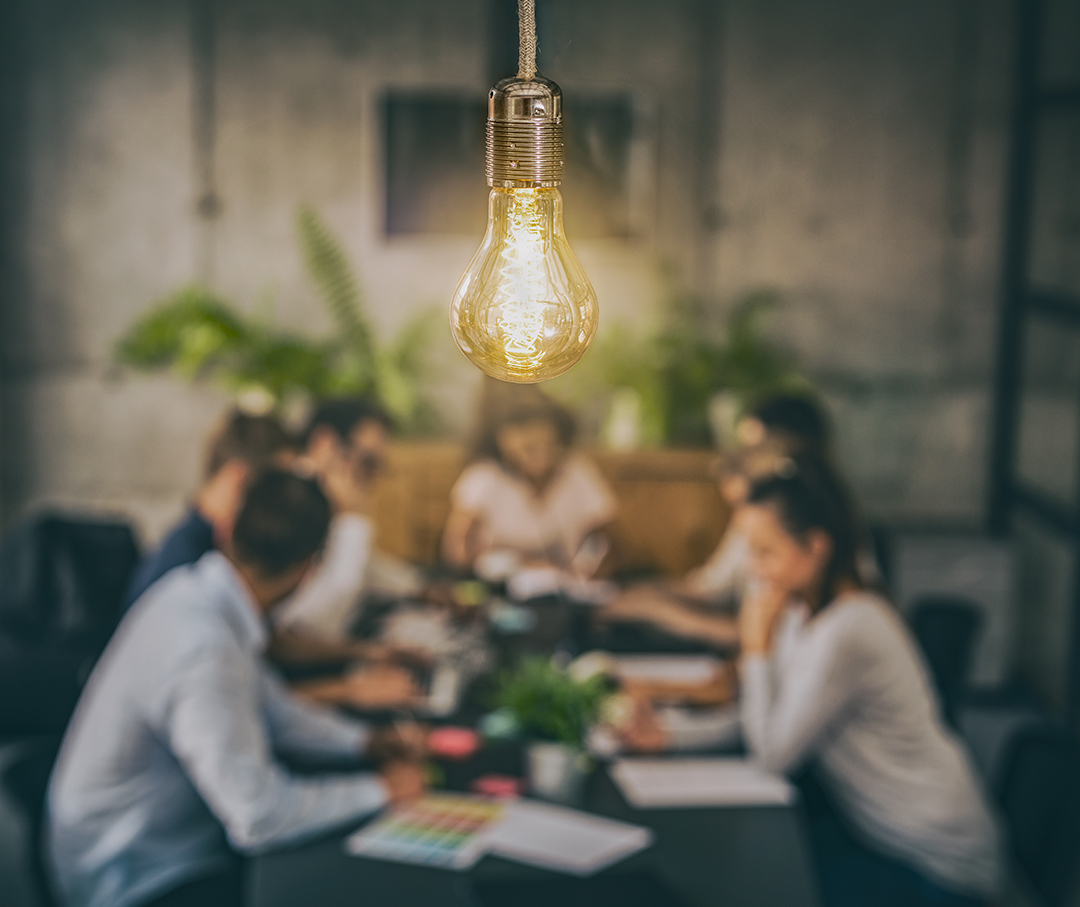 People sitting beneath a light bulb having a meeting.